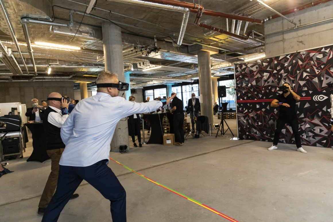 Drei Männer haben Virtual reality brillen auf in einer halle und spielen...