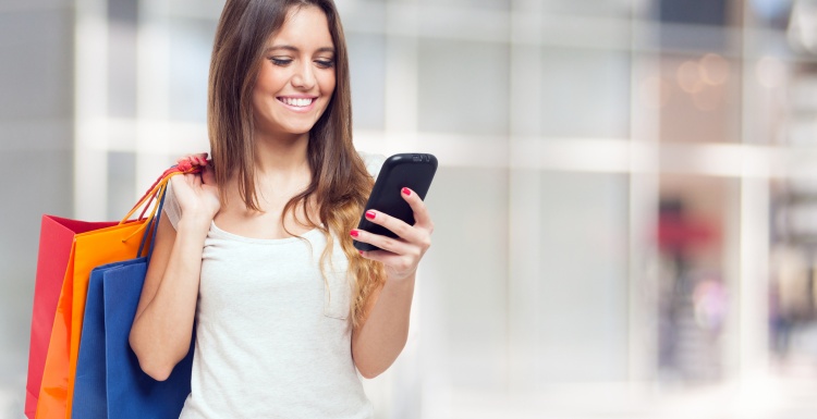 Foto: Frau mit Einkaufstüten beim Shoppen geht per Smartphone ins Internet;...