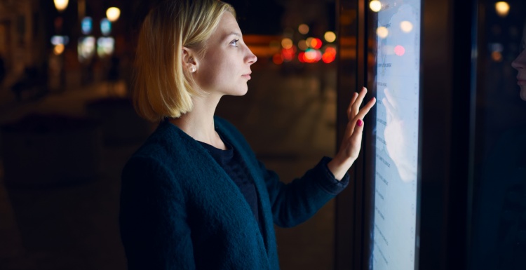 Foto: Frau berührt interaktiven Touchscreen auf der Straße bei Nacht;...
