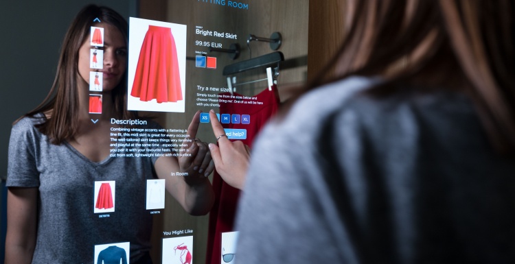 Foto: Frau benutzt einen digitalen Touch-Bildschirm in einer Umkleidekabine;...