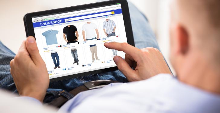 Mann von hinten, der auf einem Tablet online shoppt....