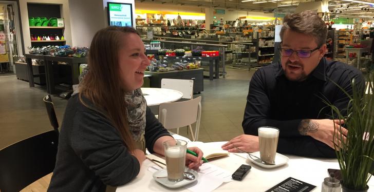 Eine junge Frau und ein Mann sitzen an einem Tisch und trinken Kaffee...