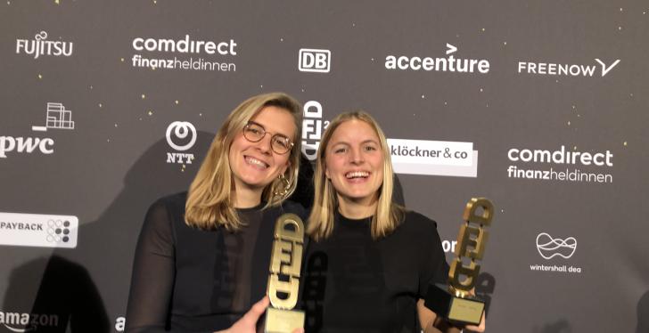 Zwei Frauen halten goldenen Award in die Kamera