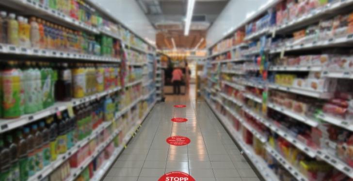Rote Punkte auf dem Boden in einem Supermarkt markieren den vorgegebenen Abstand...