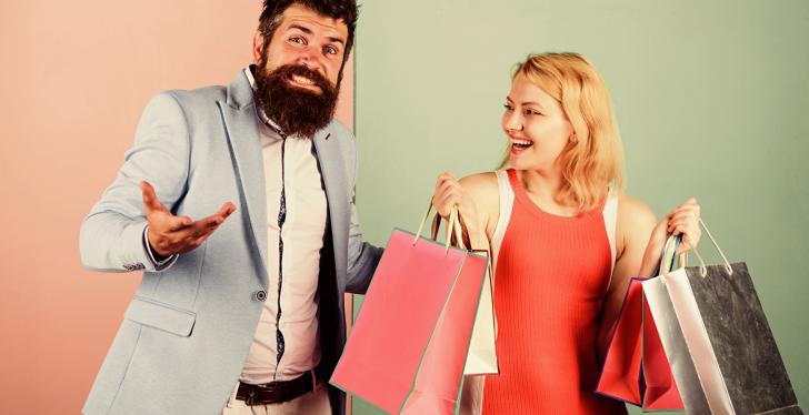 Ein Mann und eine Frau lachen und tragen Einkaufstüten...