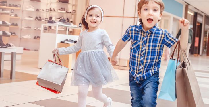 Kinder laufen Hand in Hand durchs Einkaufszentrum