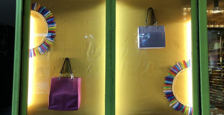 Ein beleuchtetes Schaufenster mit gelbem Hintergrund und zwei Handtaschen und...