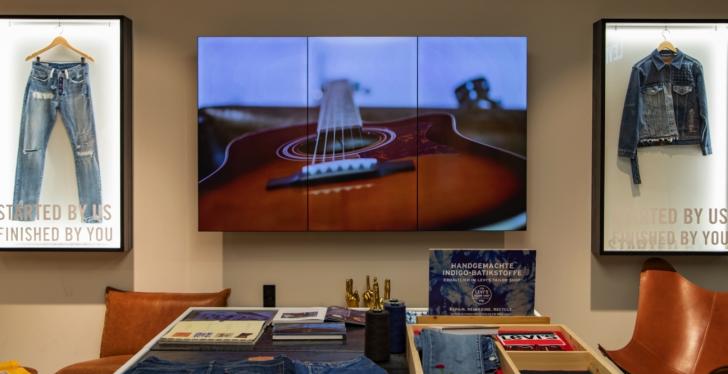 Ein digitaler Bildschirm mit Foto einer Gitarre in einem Jeansgeschäft...
