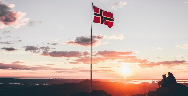Eine norwegische Flagge vor einem Sonnenuntergang