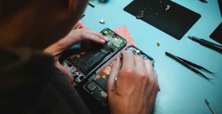 Ein Mann repariert ein Smartphone; Copyright: Kilian Seiler/Unsplash...