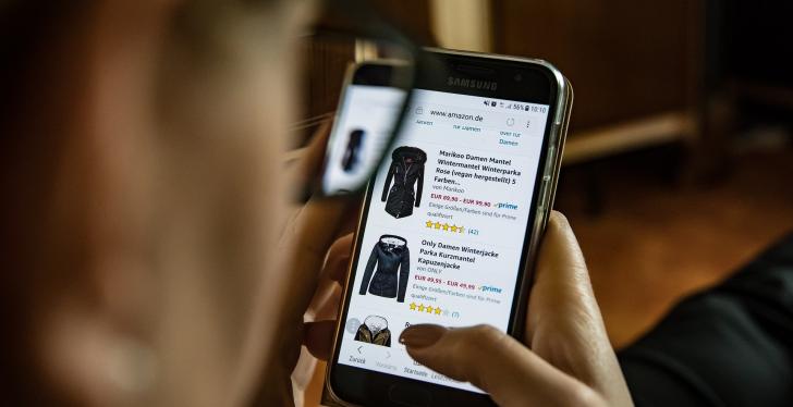 Eine Person schaut auf einem Smartphone Produkte auf Amazon.de an; copyright:...