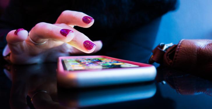 Eine Hand mit lackierten Nägeln tippt auf einem Smartphone; copyright: Rob...