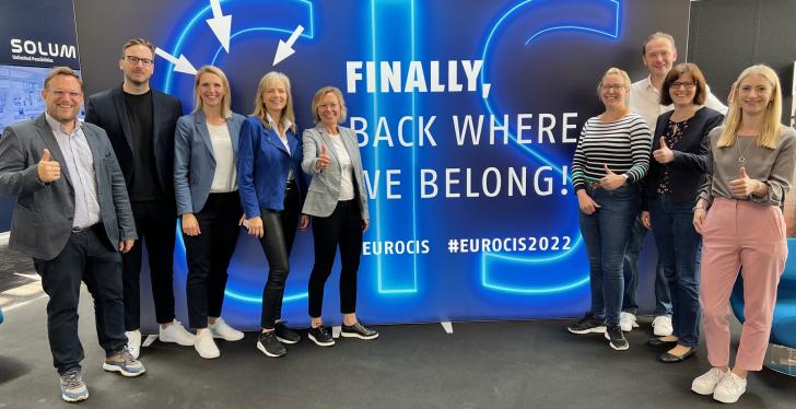 Das Team der EuroCIS 2022 vor einer Wand mit der Aufschrift Finally back where...