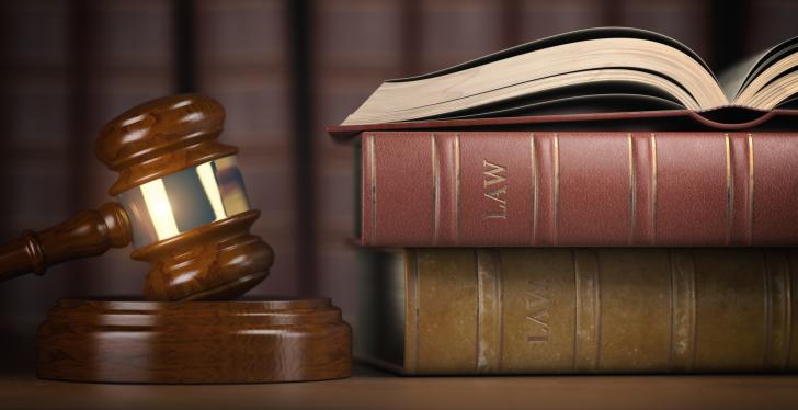 Ein Richterhammer liegt neben drei alten Gesetzbüchern; copyright:...