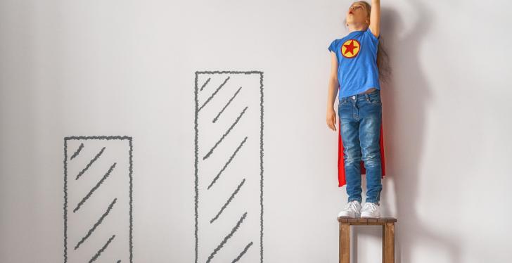 Ein Kind mit einem Supermann-Kostüm steht auf einem Hocker...