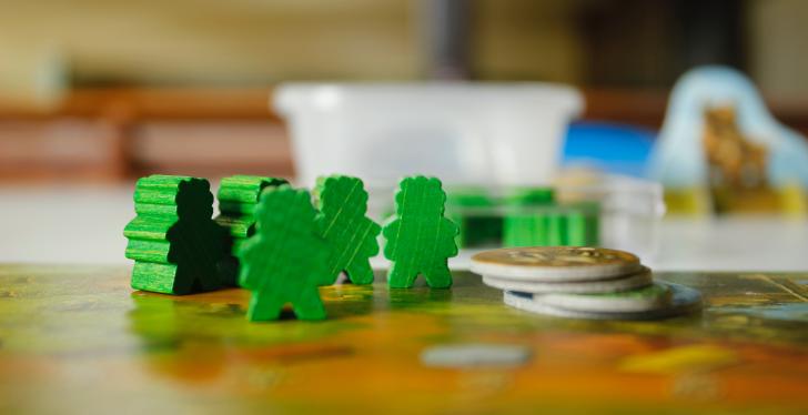 Grüne Figuren und Münzen auf einem Spielbrett