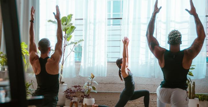 Drei Personen machen Yoga in einem großen Raum