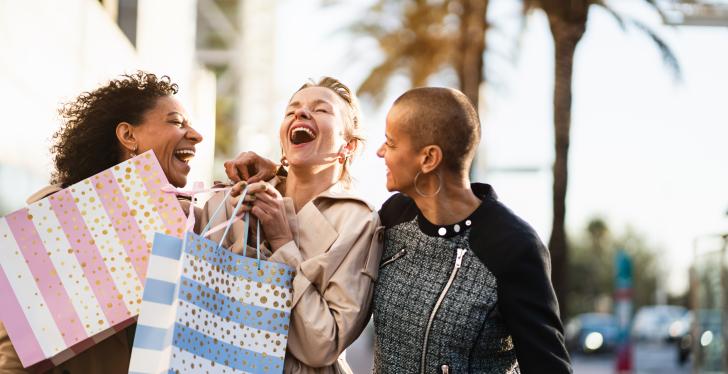 Drei Frauen lachen mit Einkaufstüten in den Händen...