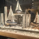 Kleine Seegelboote und Brillen auf Sand in einem Schaufenster...