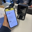 Smartphone mit Bestellbestätigung und Barcode wird vor einen stationären...