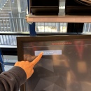Hand tippt auf dem Bildschirm Kleinpaket an, um die passende Kartonage für die...