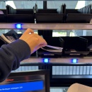 Person nimmt Beileger aus einem Regalfach mit blauer Beleuchtung zur...