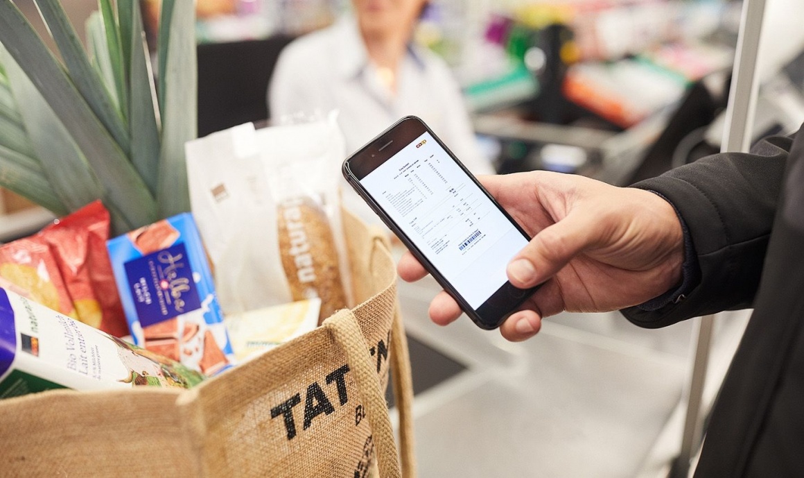 Ein digitaler Kassenzettel auf einem Smartphone, das jemand im Supermarkt in...