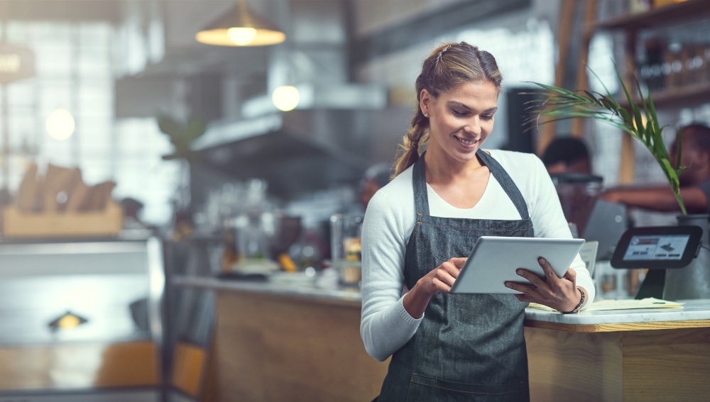 Eine Mitarbeiterin in einem gastronomischen Betrieb bedient ein Tablet-PC an...