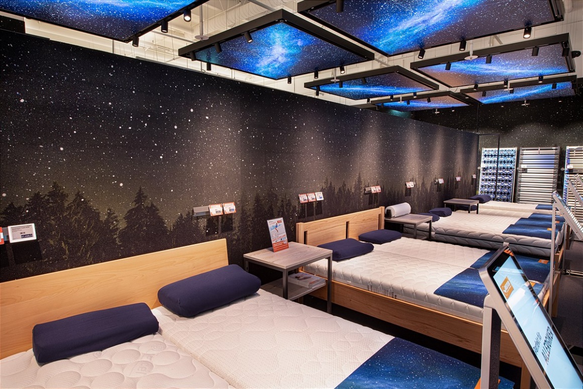 Mehrere Betten vor einem künstlichen Sternenhimmel in einer Ausstellungshalle...