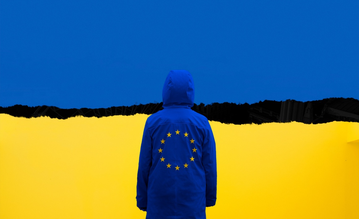 Eine Person mit dem Symbol der EU auf der Rückseite ihrer Jacke blickt auf...