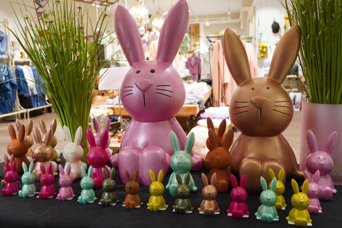 Viele bunte Hasen aus Plastik, aufgestellt in einem Verkaufsraum für Bekleidung...