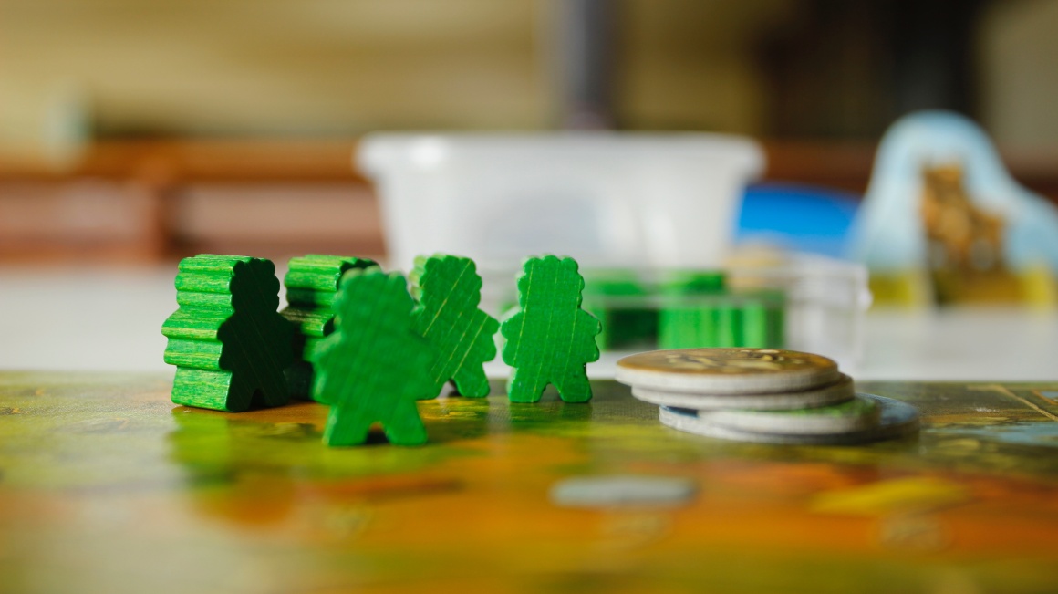 Grüne Figuren und Münzen auf einem Spielbrett