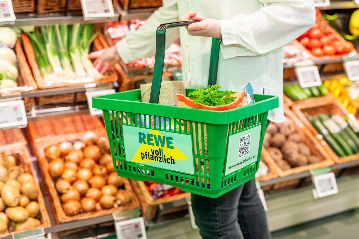 Eine Person mit einem Einkaufskorb vor dem Gemüse