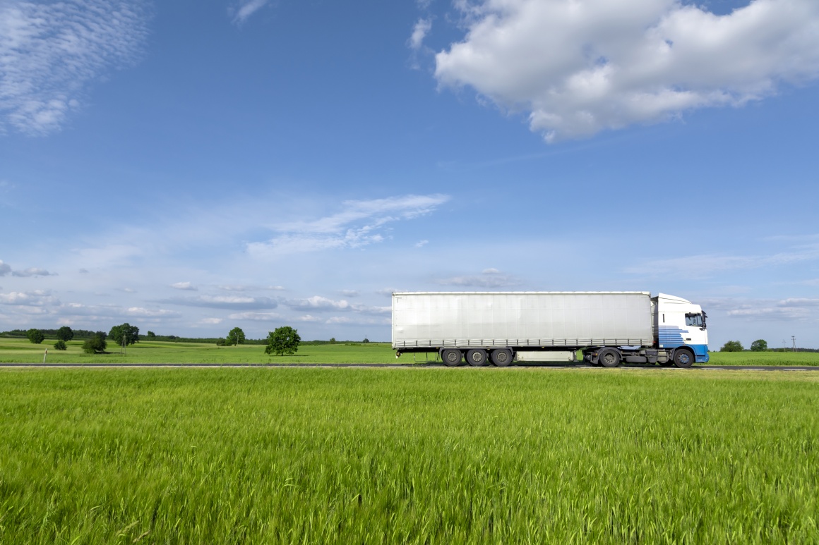 Ein LKW der durch eine grüne Landschaft fährt.