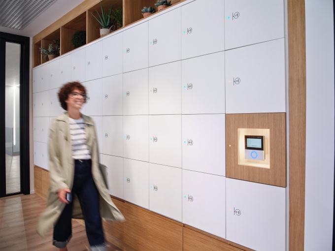 Eine Frau geht an einem Locker System vorbei.