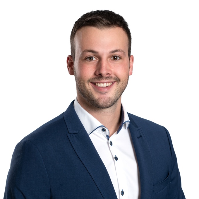 Lukas Ackermann trägt einen blauen Anzug und lächelt in die Kamera....