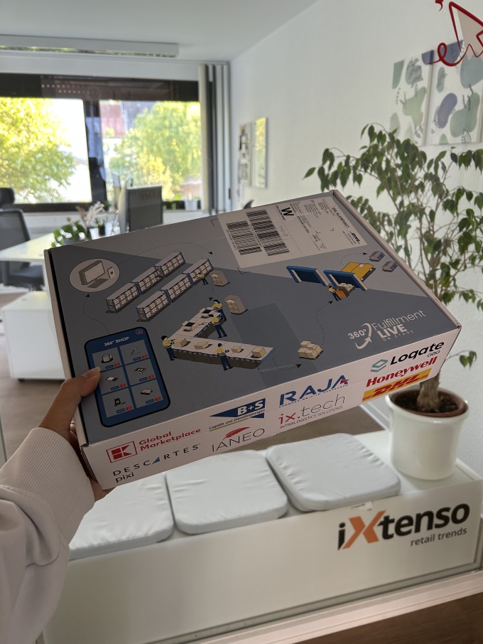 Versandkarton wird vor dem iXtenso-Logo im Büro präsentiert....