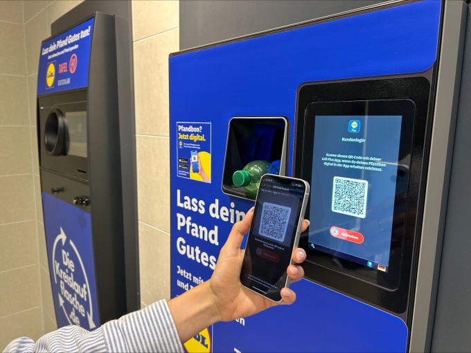 Hand hält ein Smartphone vor den QR-Code-Scanner eines Lidl-Leergutautomaten,...