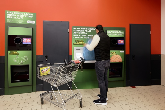 Mann stellt gesammeltes Leergut in einen Rückgabeautomaten bei Kaufland,...