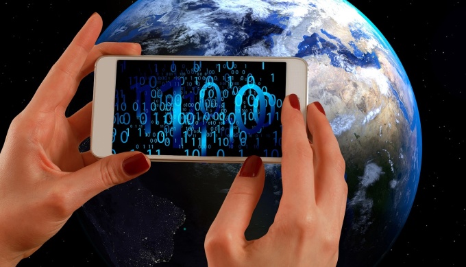 Smartphone wird vor Weltkugel gehalten