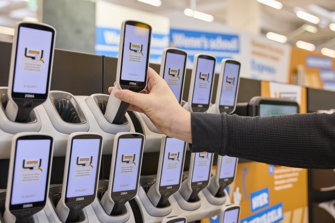Person nimmt Handscanner im Supermarkt aus der Station...