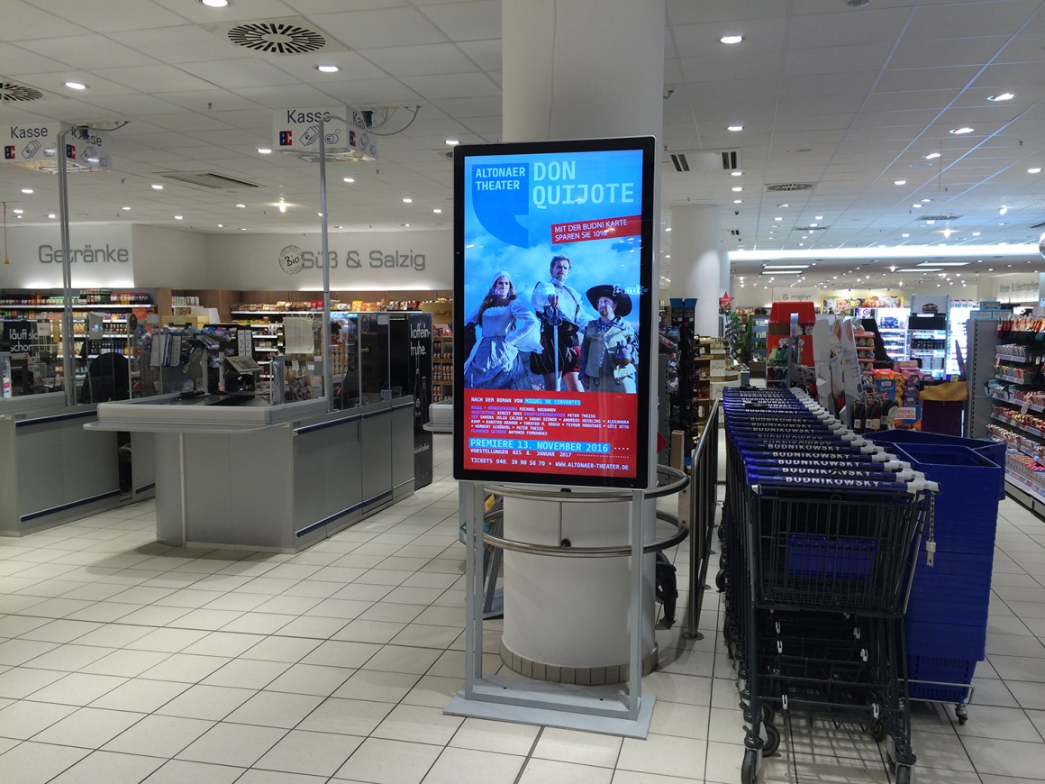 Foto: Werbestele mit Bildschirm vor Kassen und Warenregalen eines...