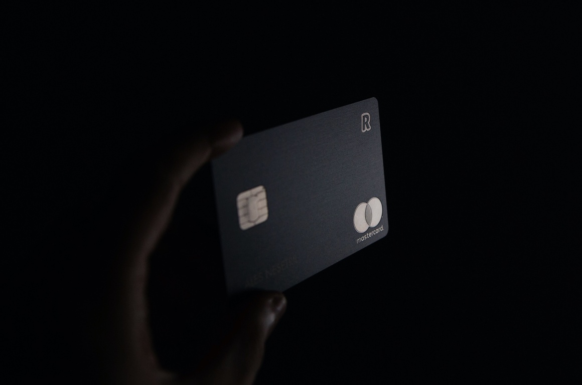 Kreditkarte in einer Hand auf schwarzem Hintergrund...
