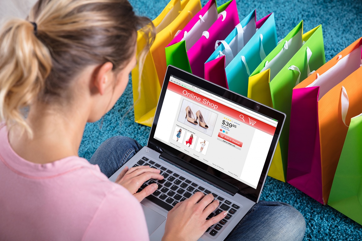 Eine Frau beim Online-Shopping am Laptop; im Hintergrund: viele bunte...