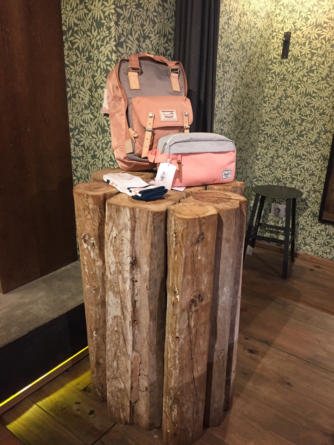 Ein Rucksack und eine Tasche sind auf einem Holzstamm drapiert...