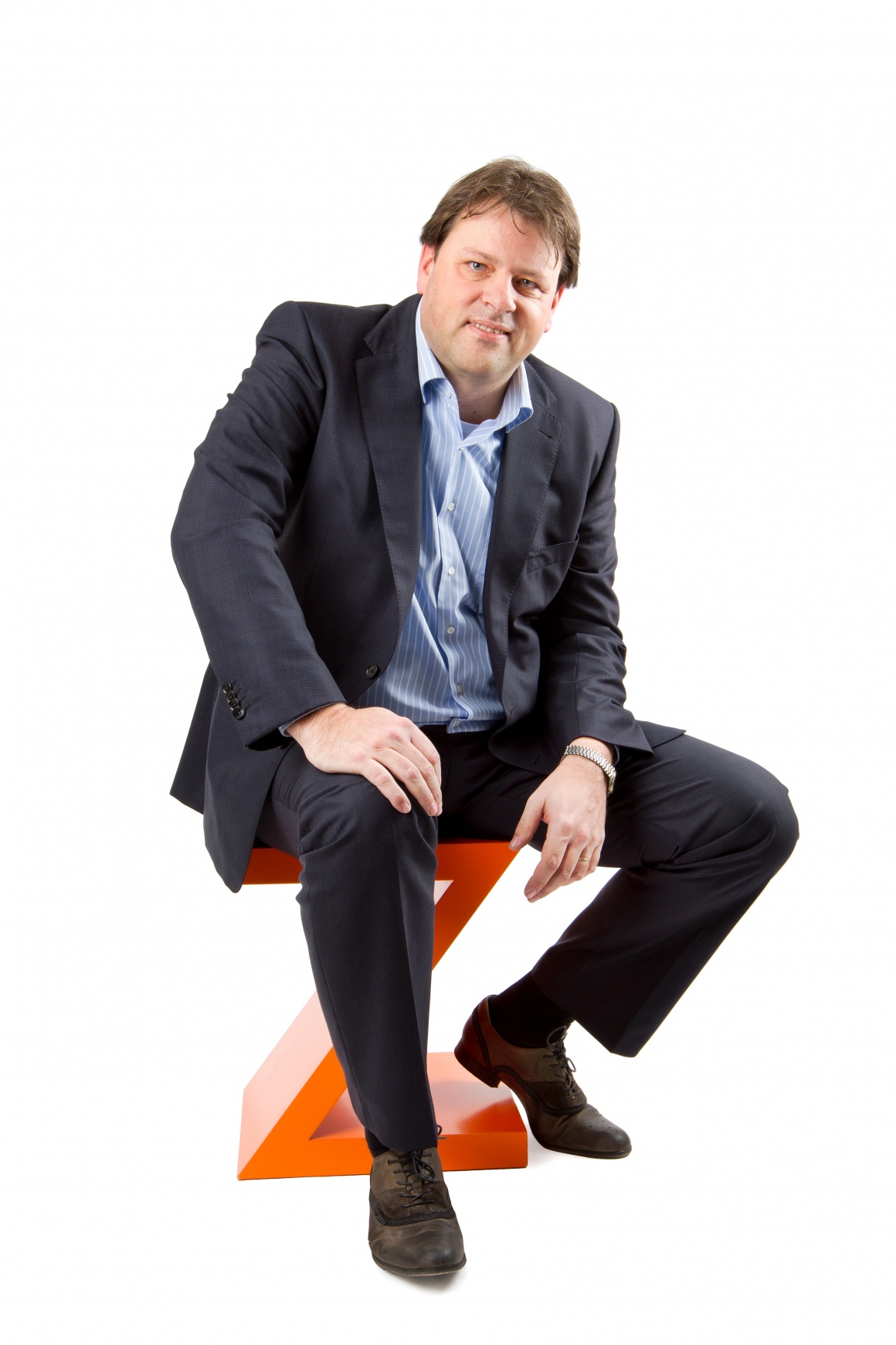 Ein Mann im Anzug sitzt auf einem orangenen Z