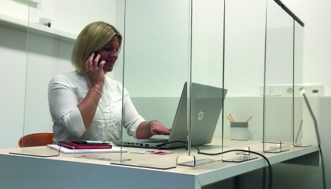 Frau im Büro hinter Plexiglasscheiben
