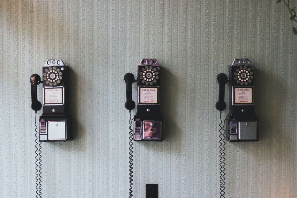 3 alte Telefone mit Wählscheiben an einer Wand montiert...