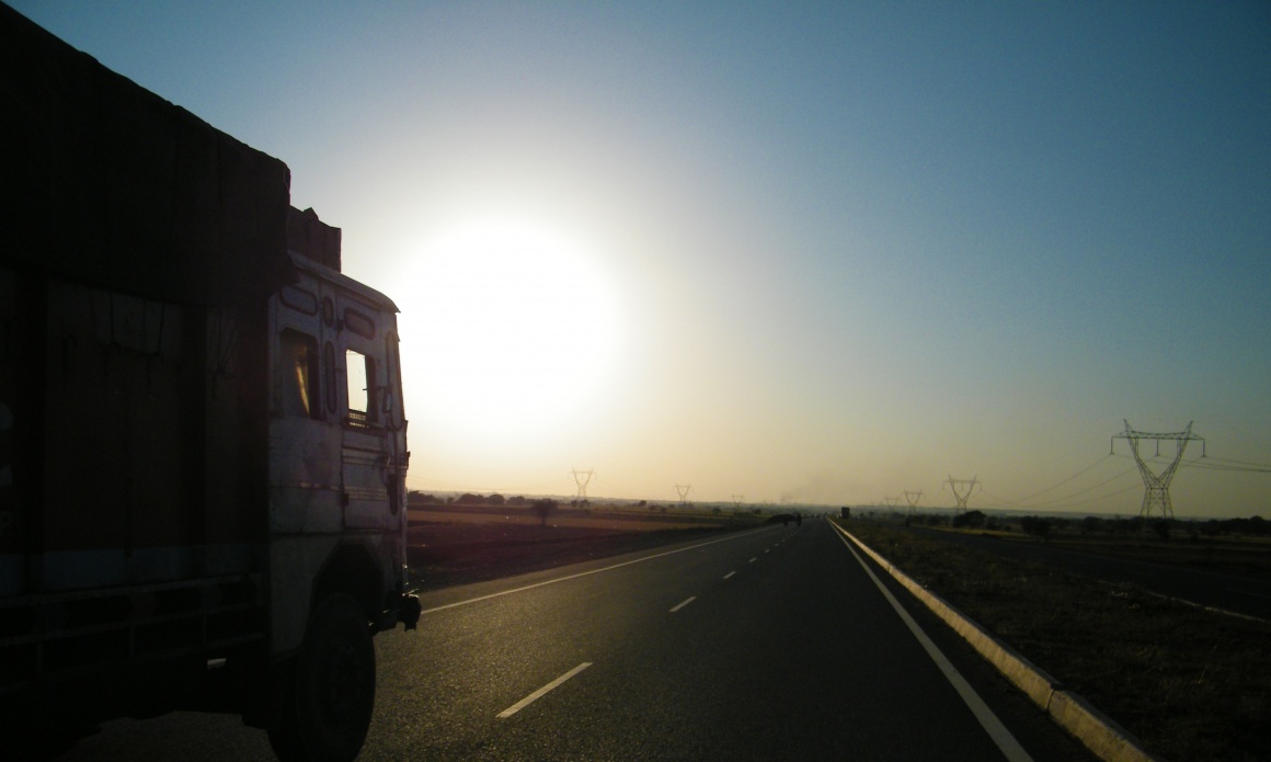 Ein LKW fährt auf einer geraden Straße in den Sonnenuntergang...