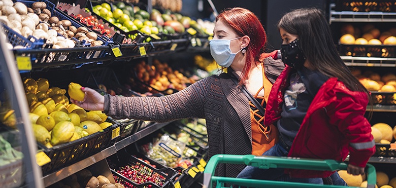 Zwei Frauen stehen im Supermarkt mit Maske am Obstregal-...